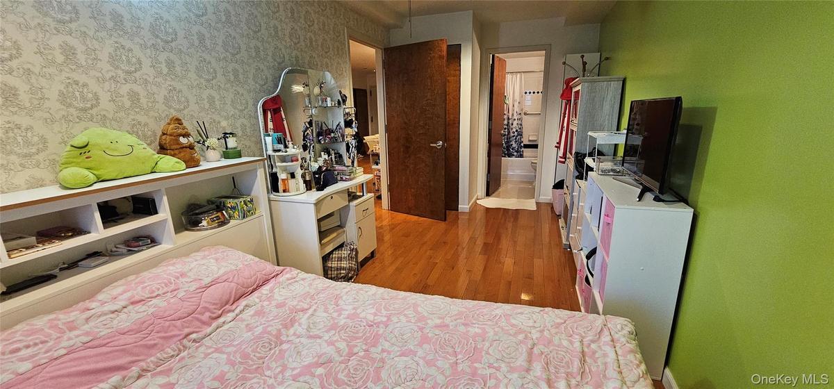 Bedroom with light wood-type flooring and wallpapered walls