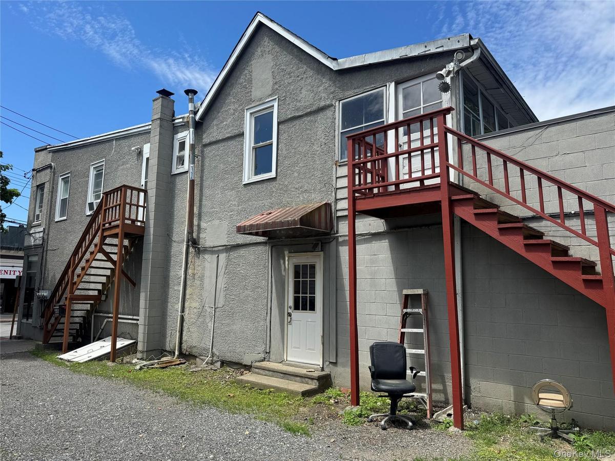 The residential unit offers three generously sized rooms, a full bathroom, powder room, kitchen, and a sun-filled sunroom, providing flexible living s