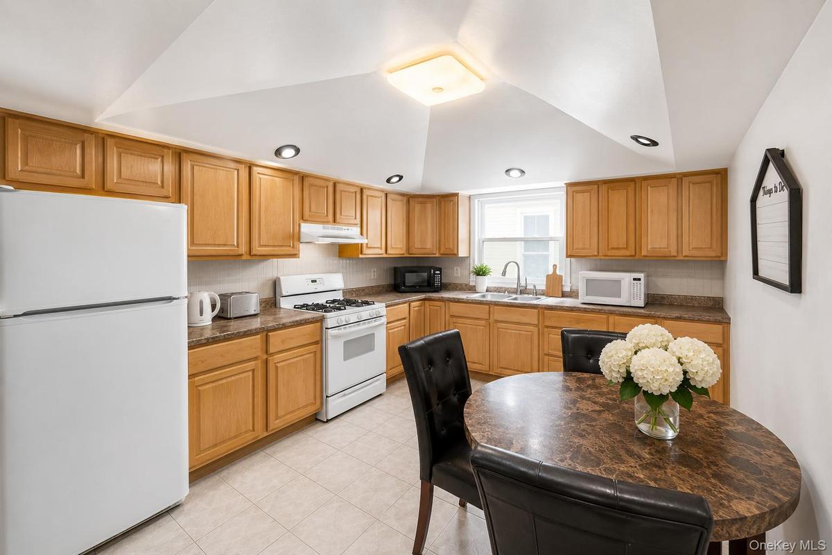 Kitchen featuring abundant wood cabinetry, white appliances, recessed lighting, and a window above the sink