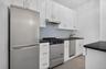Streamlined kitchen featuring white cabinetry, dark countertops, stainless steel appliances, a tile backsplash, and wood-finish flooring