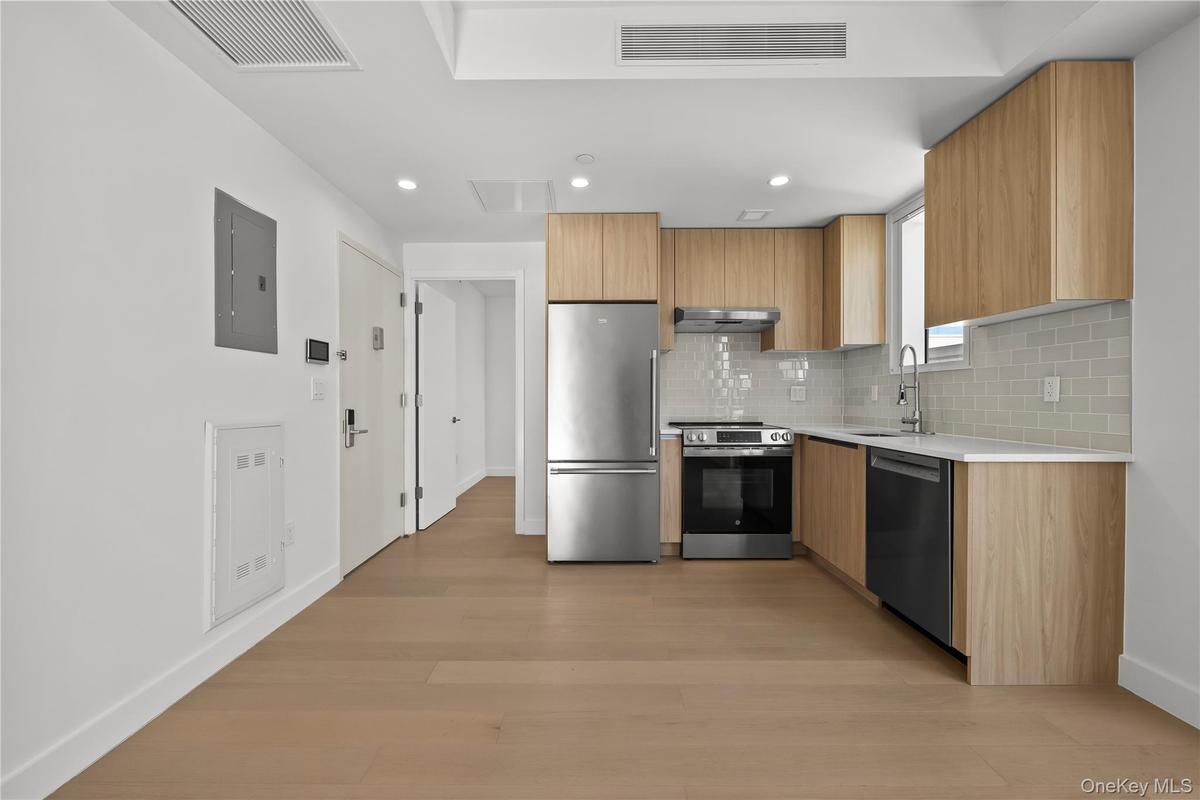 Kitchen featuring modern cabinets, stainless steel appliances, backsplash, light stone countertops, and light wood-style floors
