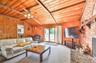 Carpeted living room with wood ceiling, ceiling fan, wooden walls, and a fireplace