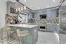 Custom cabinetry with integrated wine rack, stainless steel top of the line appliances, white quartz countertops, over-sized porcelain tile flooring,