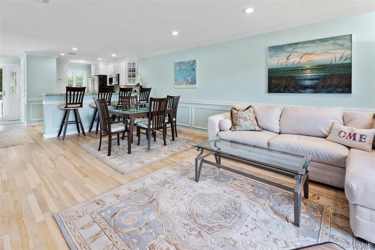Living area with recessed lighting, a decorative wall, crown molding, and light wood-type flooring