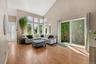 Vaulted ceiling with a wall of windows, wood-finish flooring, and a sliding glass door