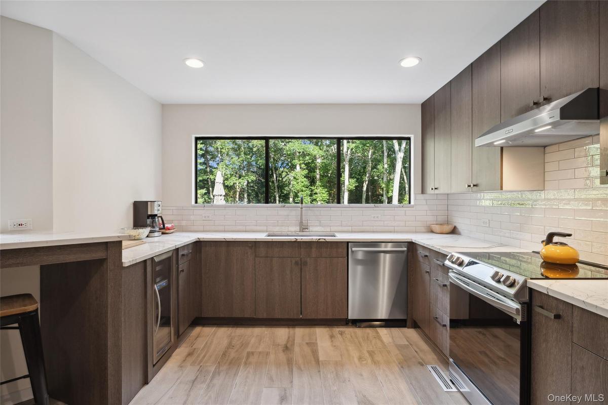 Kitchen with stainless steel appliances, a kitchen bar, a peninsula, light stone counters, and recessed lighting