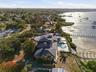 From a westward aerial vantage view highlights the estate architectural presence, capturing three points of the mansion against a spectacular waterfro