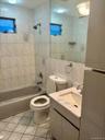Tile flooring, full-height wall tiling, built-in bathtub, vanity with integrated sink, and wall-mounted mirror