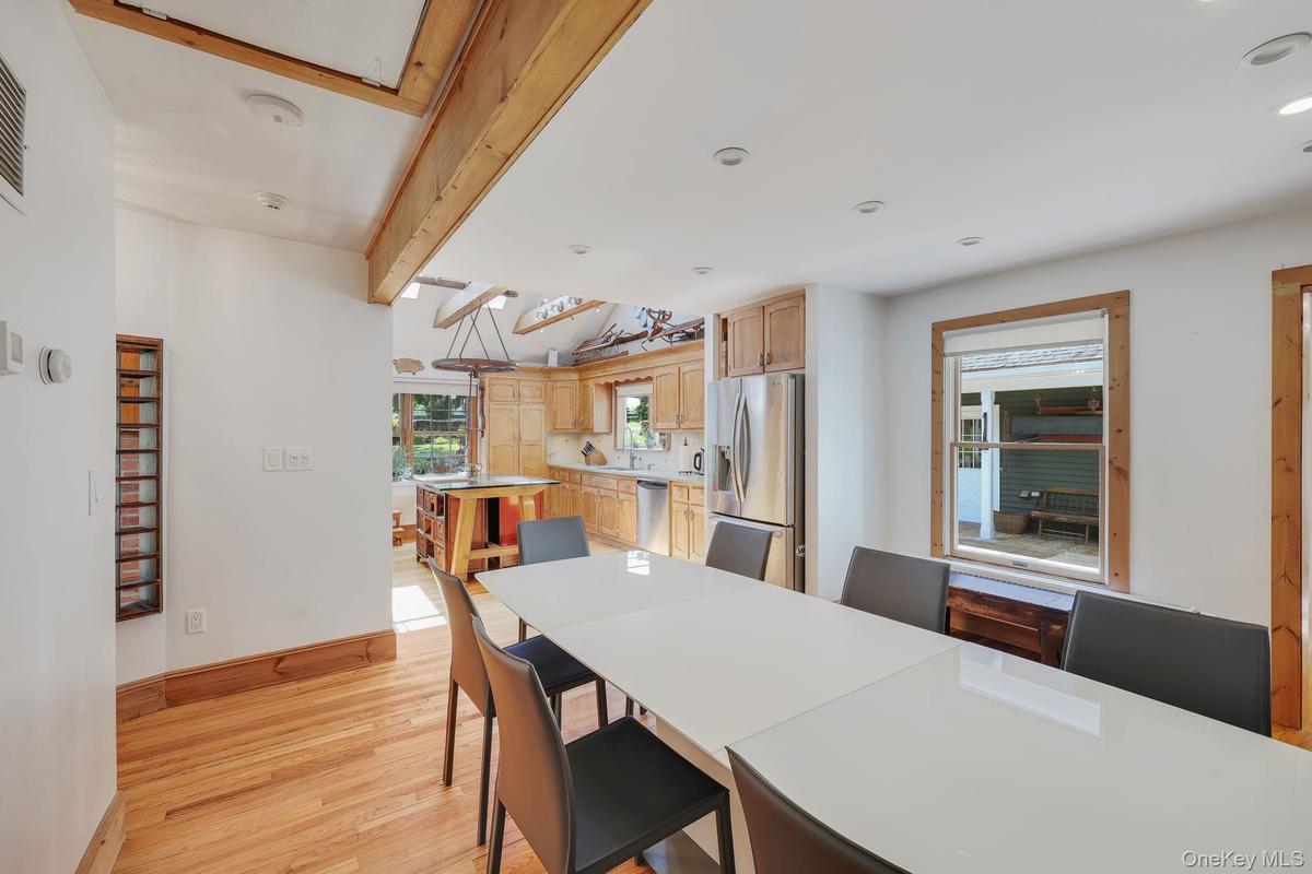 Open-concept dining and kitchen areas with hard wood flooring, exposed ceiling beams and recessed lighting.