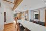 Open-concept dining and kitchen areas with hard wood flooring, exposed ceiling beams and recessed lighting.