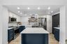 Renovated kitchen with navy shaker cabinetry, white marble counters and backsplash, farmhouse apron sink, brass hardware, and a marble-topped center i