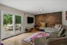 Living area featuring hardwood flooring, a brick accent wall, recessed lighting, and a sliding glass door providing access to an outdoor deck