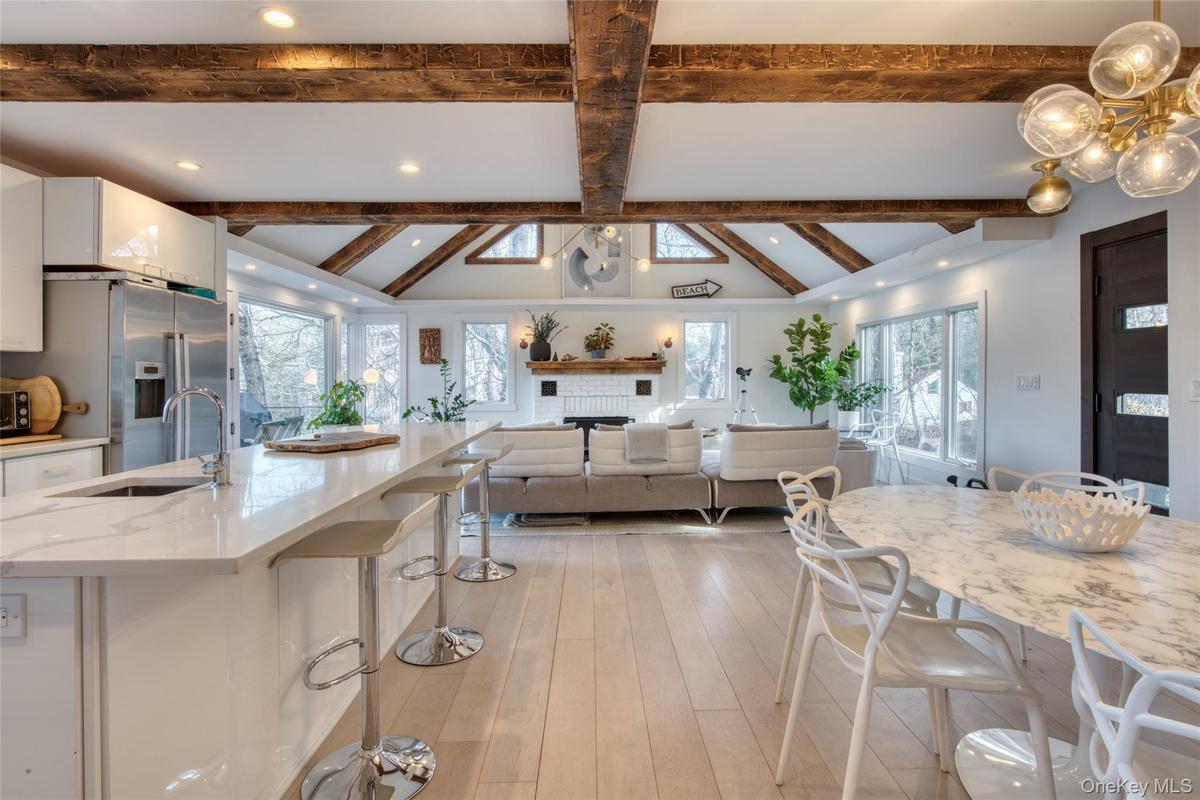 Kitchen with a breakfast bar, vaulted ceiling with beams, white cabinets, high quality fridge, and a sink