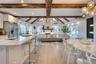 Kitchen with a breakfast bar, vaulted ceiling with beams, white cabinets, high quality fridge, and a sink