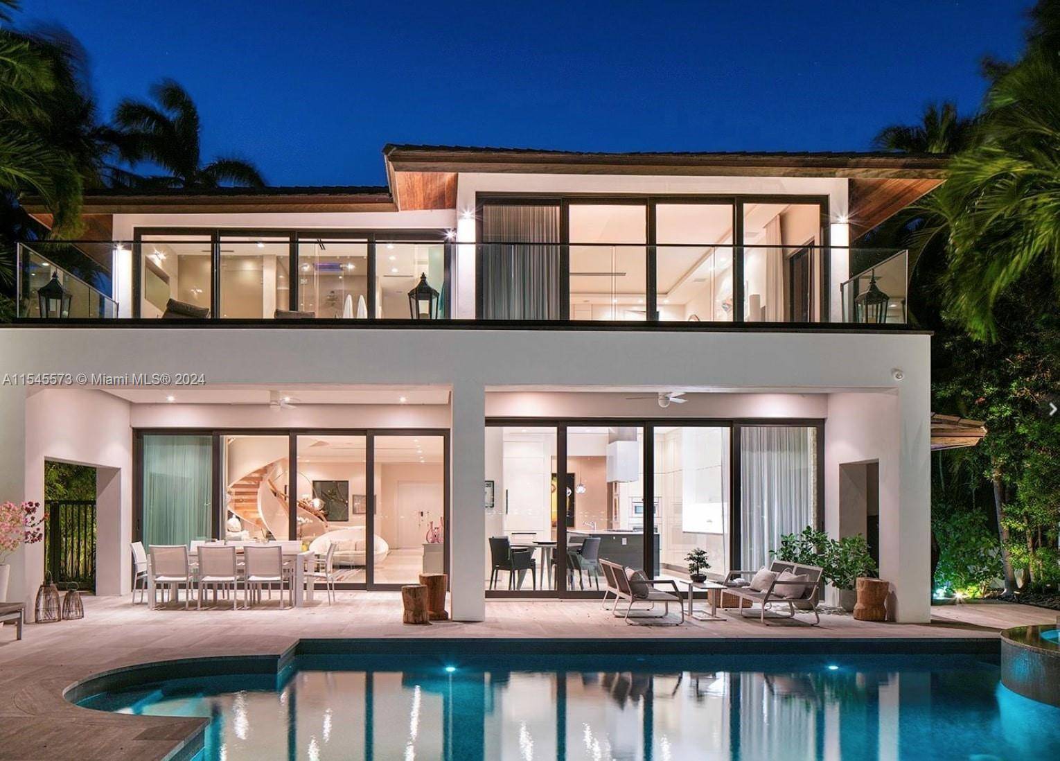 Lush tropical landscaping envelops this exquisite contemporary waterfront residence with mesmerizing vistas of Miami Beach from its expansive floor to ceiling telescopic sliding glass doors.