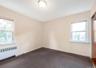 Carpeted empty room featuring radiator heating unit and baseboards