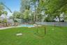 Beyond the pool, an expansive level lawn provides exceptional space for play, sports, and outdoor recreation, all surrounded by mature trees and lush
