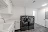 The beautifully designed laundry room features a sleek Electrolux front-load washer and dryer set, surrounded by abundant cabinetry and countertops f
