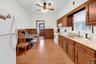 Kitchen featuring white appliances, brown cabinets, light countertops, light wood-type flooring, and a wainscoted wall