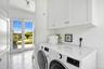 Laundry area featuring light tile patterned floors, washer and clothes dryer, ornamental molding, and cabinet space