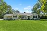 Ranch-style home with a front yard, roof with shingles, a chimney, and cooling unit
