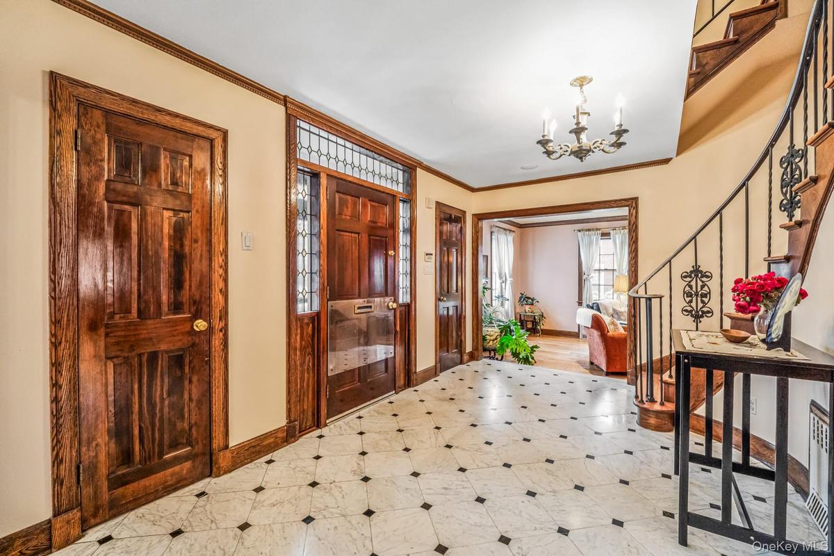 Entryway with stairway, ornamental molding, a chandelier, and light flooring