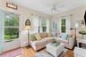 Living area featuring baseboard heating, light wood-type flooring, a ceiling fan, and crown molding