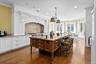Kitchen with backsplash, white cabinetry, ornamental molding, light stone countertops, and dark wood finished floors