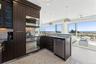 Kitchen featuring dark stone counters, a sink, appliances with stainless steel finishes, dark brown cabinets, and a peninsula