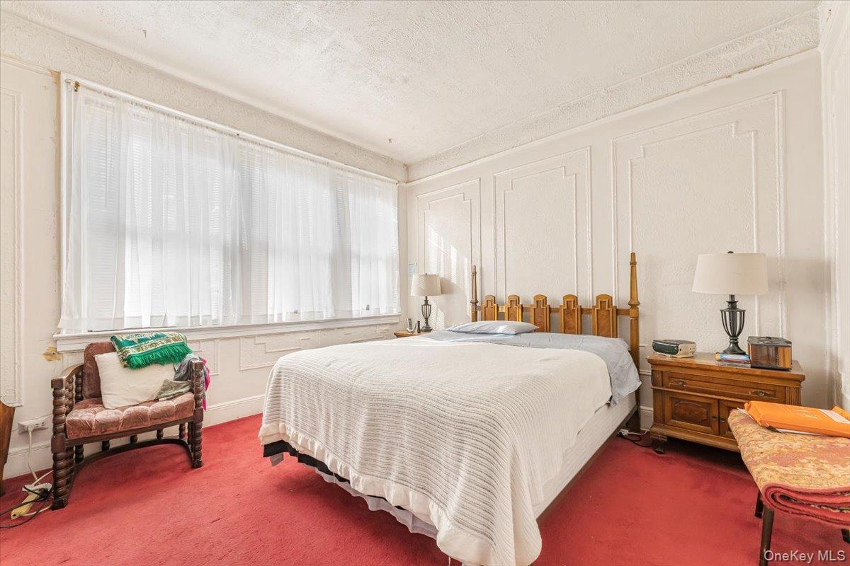 Carpeted bedroom featuring baseboards and a textured ceiling