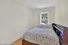Light-filled room featuring wood-finish flooring, white baseboards, and a single window with white trim