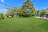 Expansive lawn area with mature trees and a paved patio