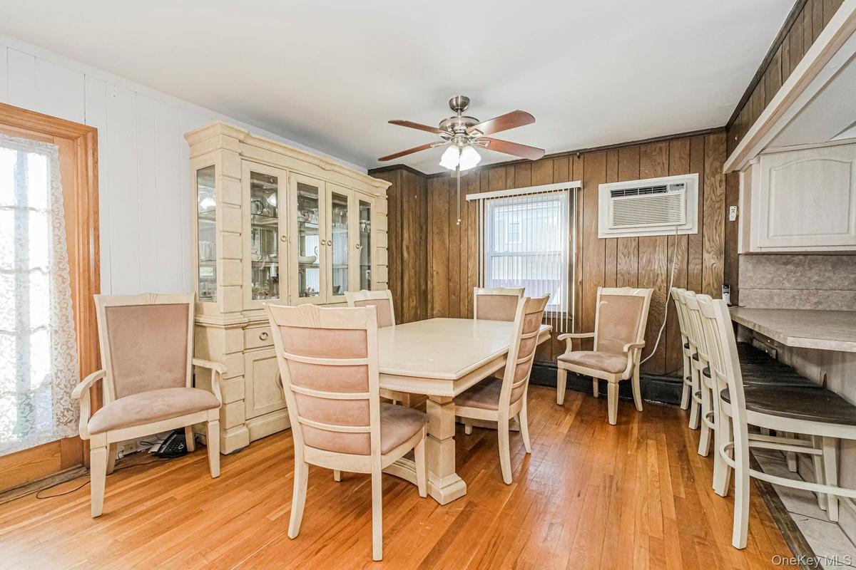 Dining area featuring wood-finish flooring, wood paneling, and a ceiling fan with integrated lighting