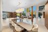 Open-plan formal dining area with large stone-top dining table, upholstered walnut chairs, oversized globe chandelier with brass stem, floor-to-ceilin