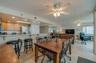 A central dining area connects to the kitchen and living space, all under ceiling fans and surrounded by windows—ideal for casual meals and gatherings