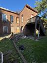 Back of house featuring brick siding, a wooden deck, a yard, a patio area, and stairway