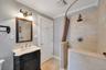 Walk-in shower with tiled walls and floor, featuring a dark bronze rainfall showerhead and control