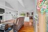 Living room with light wood-style flooring, a fireplace, lofted ceiling, wainscoting, and a decorative wall