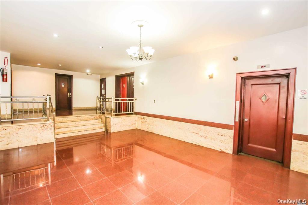 Tiled empty room with recessed lighting, a wainscoted wall, a chandelier, and tile walls