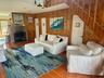 Living room featuring wood walls, wood finished floors, a ceiling fan, and a brick fireplace