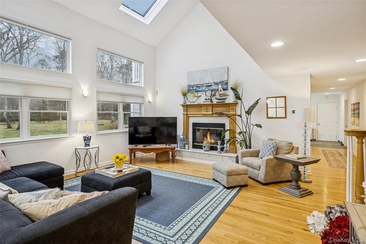 Living area featuring a skylight, a high end fireplace, high vaulted ceiling, and wood finished floors