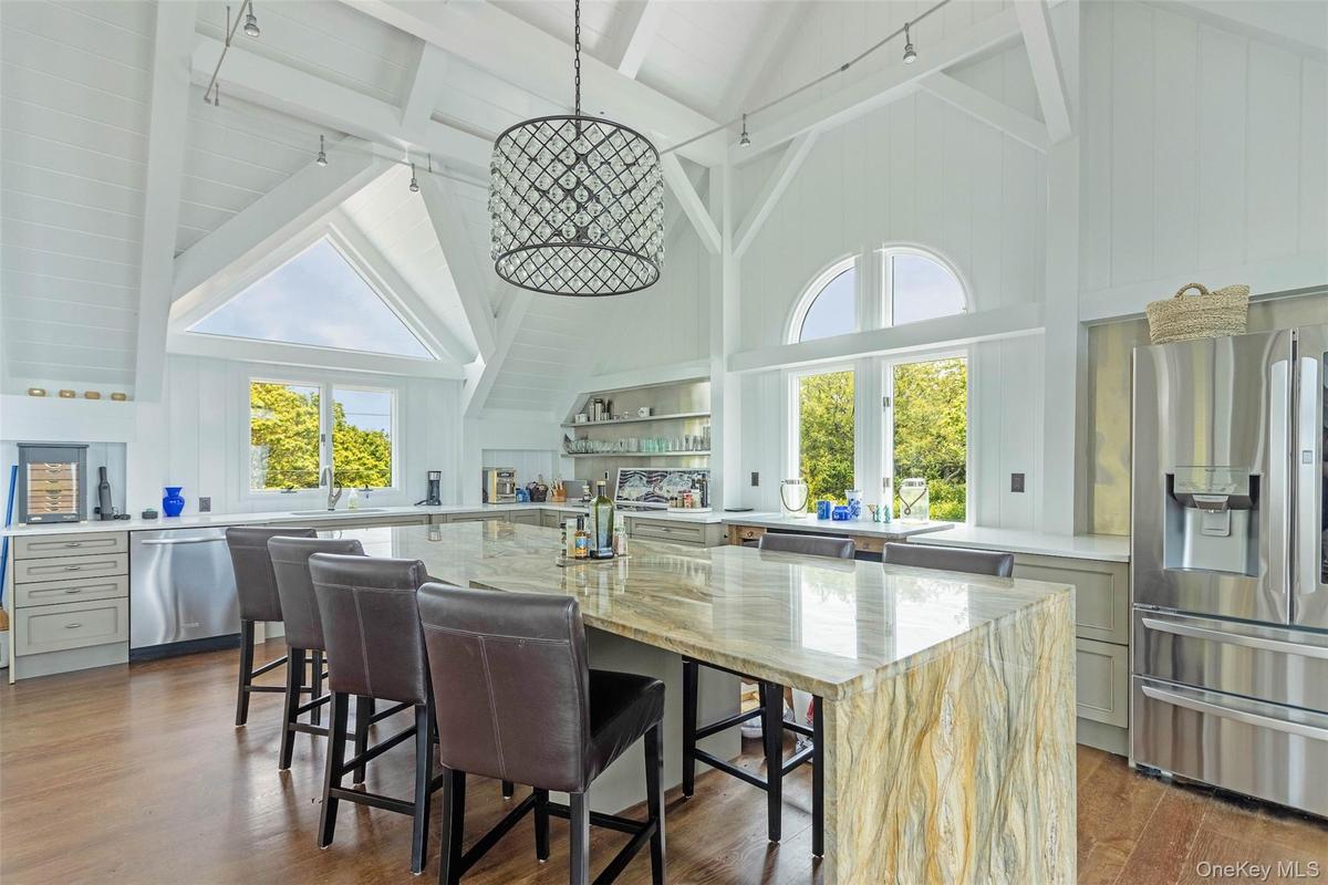 Kitchen with stainless steel appliances, high vaulted ceiling, dark wood finished floors, beam ceiling, and light stone counters