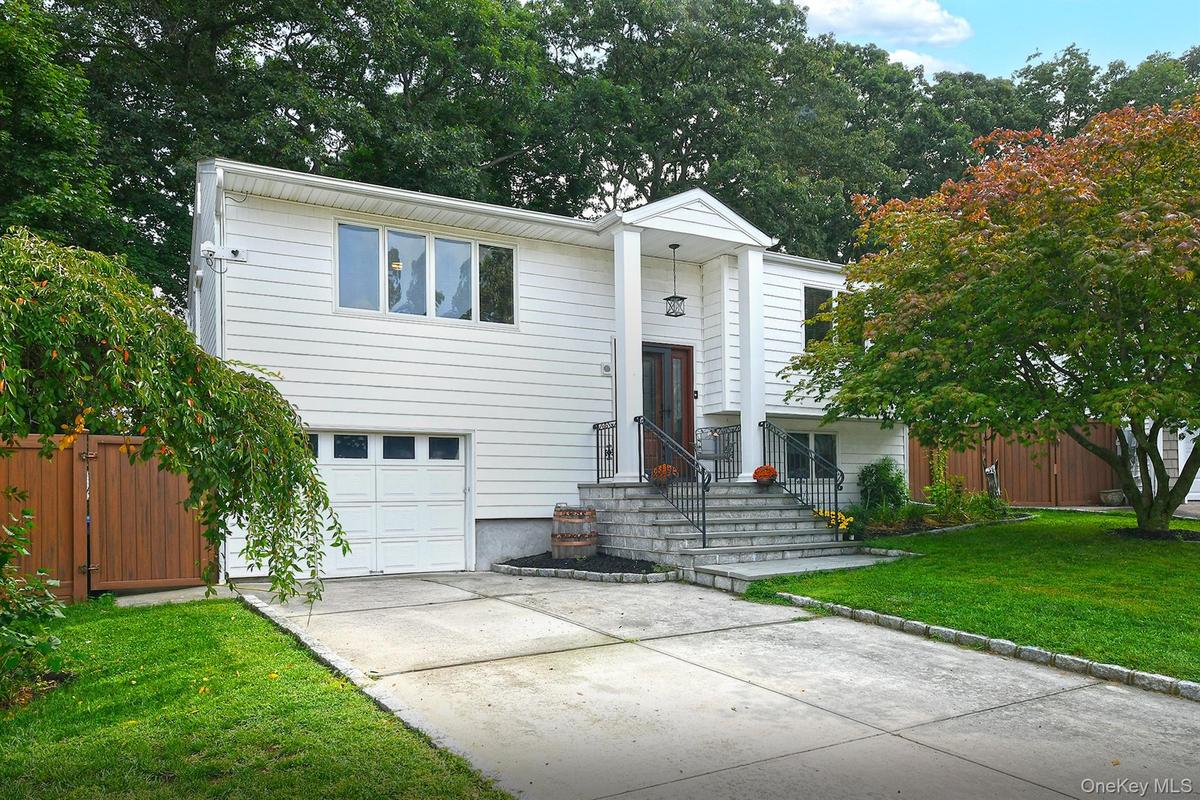 White siding exterior with a prominent covered entry, stone steps, and an attached garage with a white door