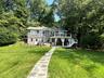 View of front facade featuring stairs, a chimney, a front lawn, a wooden deck, and a patio