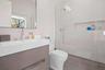 Bathroom with decorative backsplash, a tile shower, vanity, tile walls, and toilet