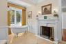 Full bathroom with a soaking tub, ornamental molding, a fireplace, a decorative wall, and a wainscoted wall