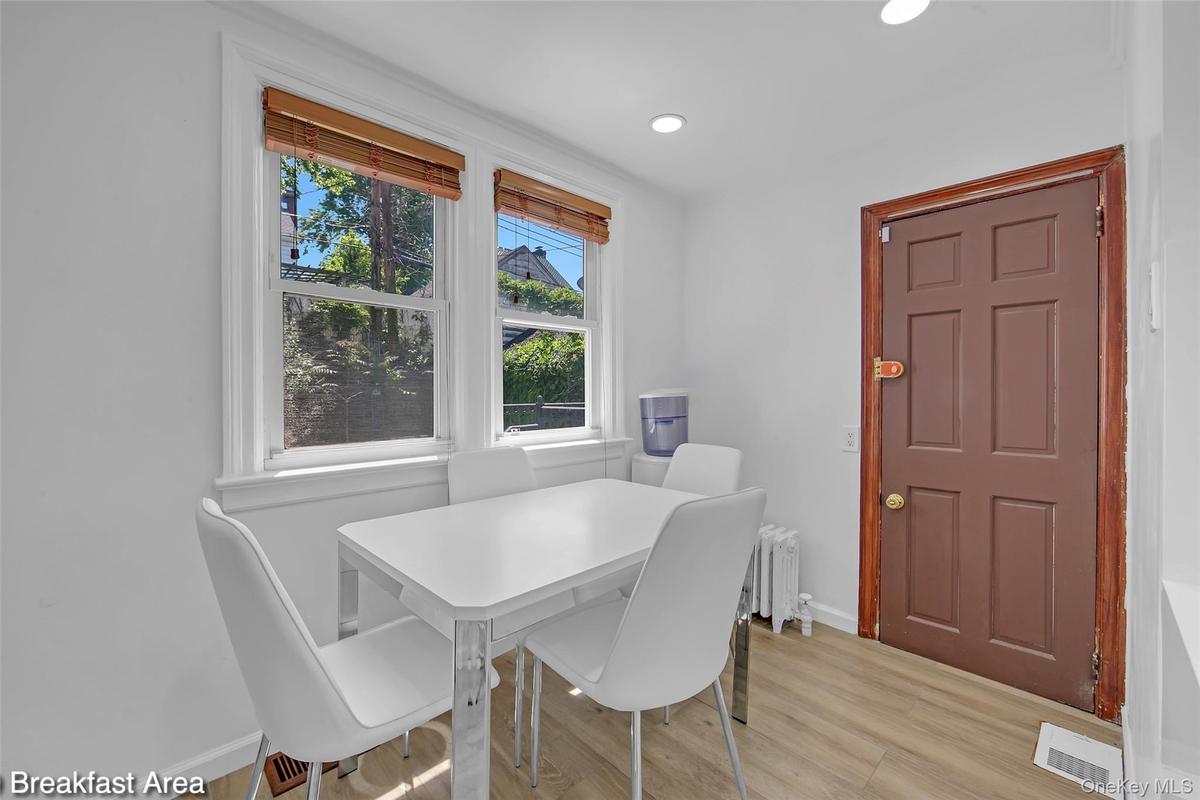Dining area with light wood-finish flooring, white walls, and recessed lighting