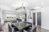 Open-concept interior featuring wood-finish flooring, a contemporary chandelier, recessed lighting, a kitchen island with seating, and dark panel door