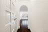 Corridor with arched walkways, dark wood-style flooring, and baseboards