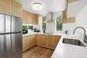 Kitchen featuring black appliances, wall chimney range hood, plenty of natural light, and light wood-style flooring